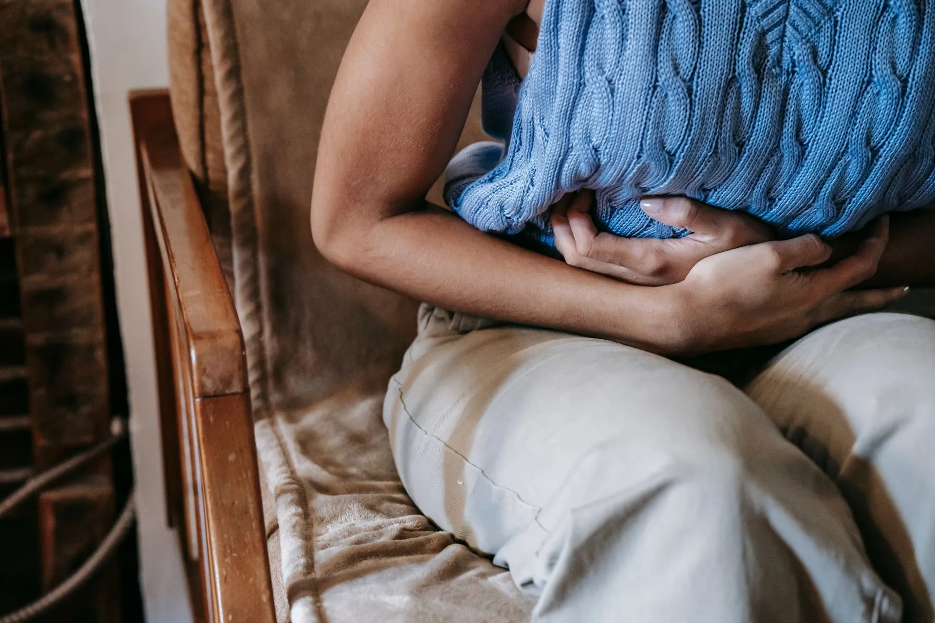 Persoon houdt de handen tegen de buik